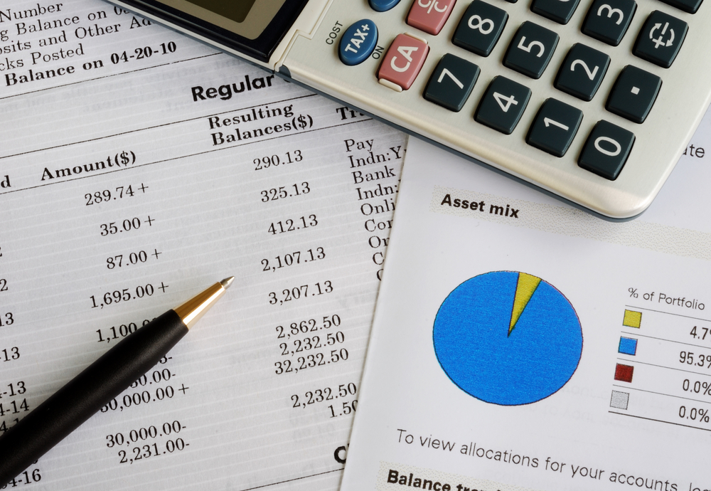 Investing documents scatterd on a table with pen and calculator